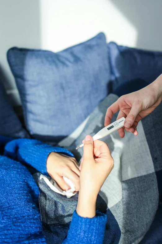 a person with a hand holding a thermometer