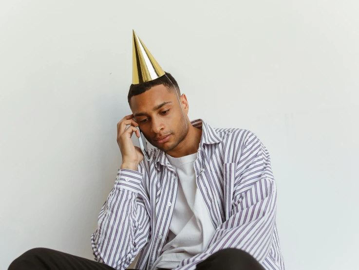 a man with a birthday hat is holding a cell phone