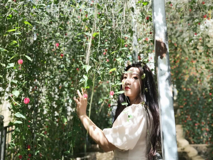 a girl in white is looking down at flowers