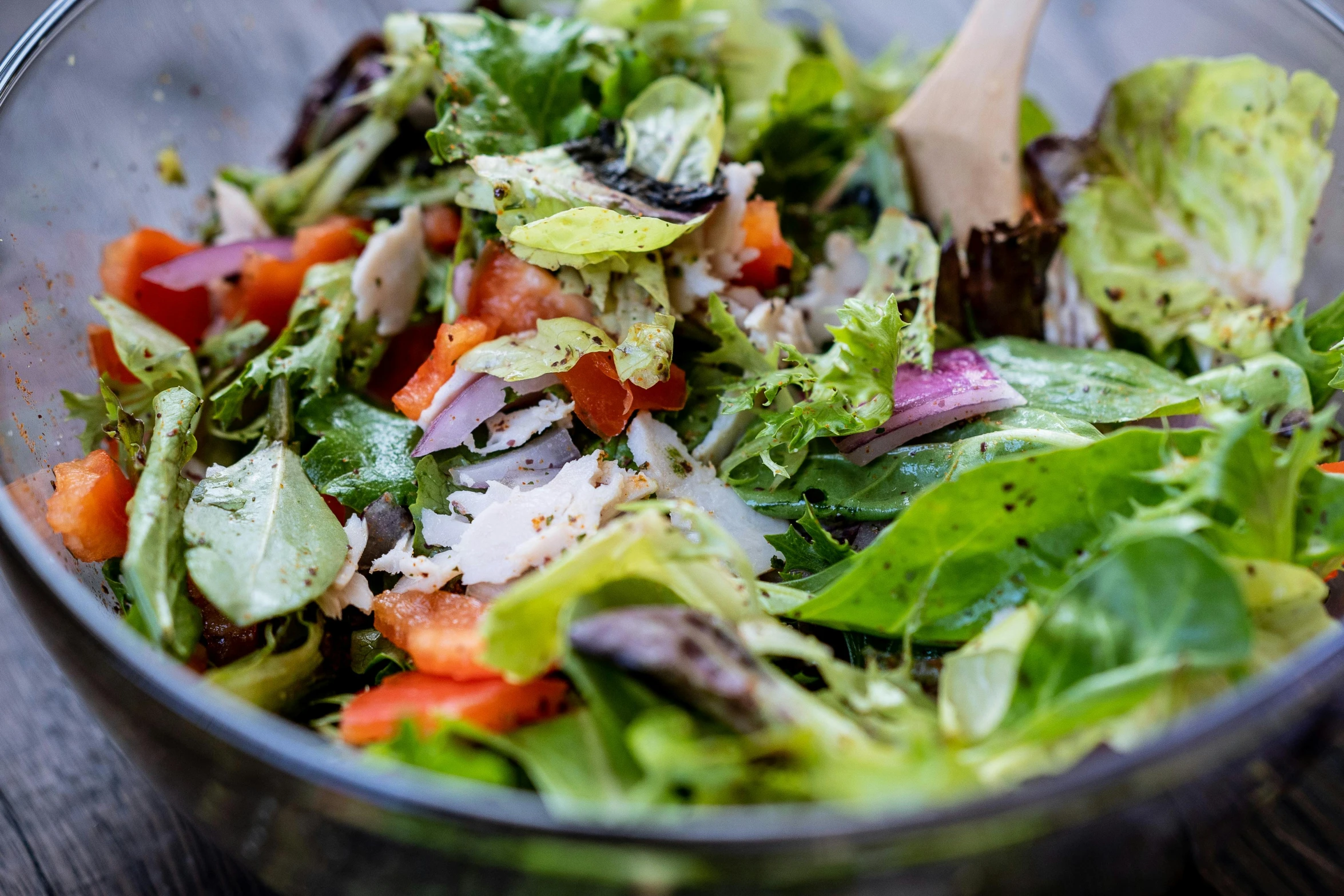 this salad is in a bowl with a wooden spoon