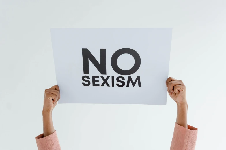 a woman holding up a no sexism sign in the air