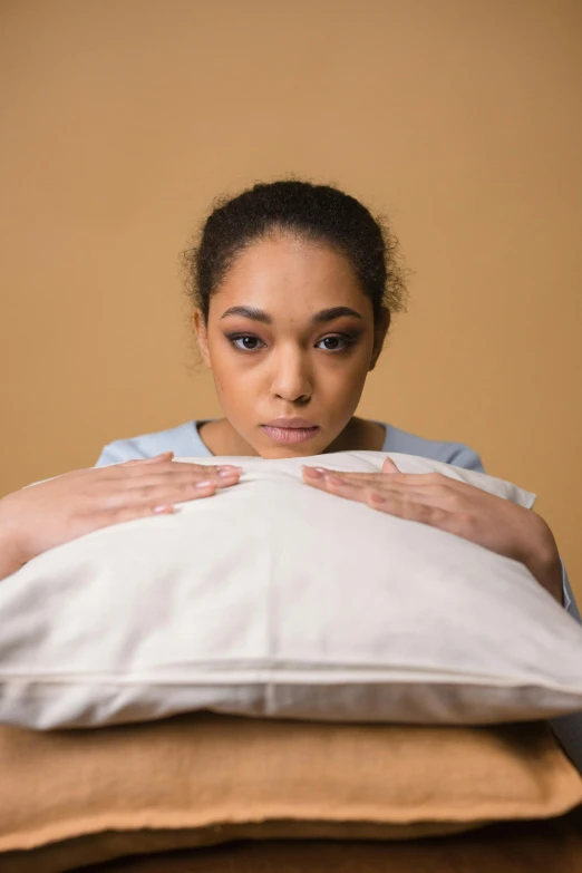 a woman covers her face with a pillow