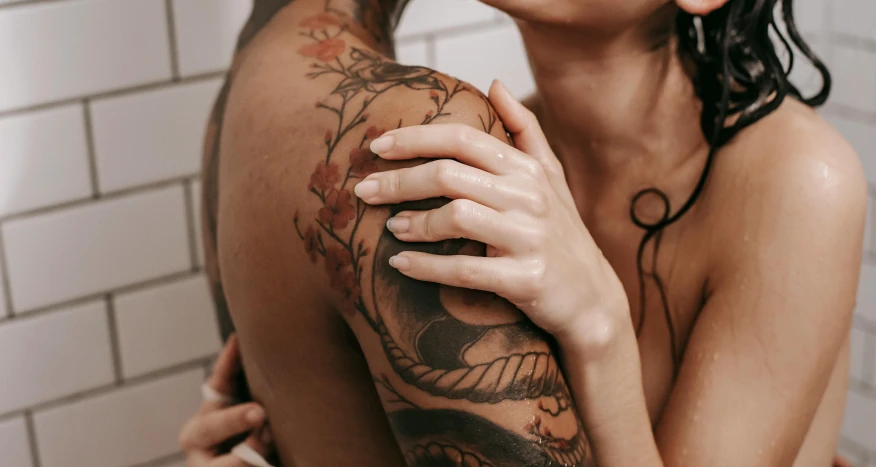 tattooed woman emcing another woman in the bathroom