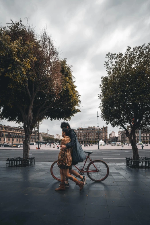 a woman walks with her backpack down the sidewalk next to a bike