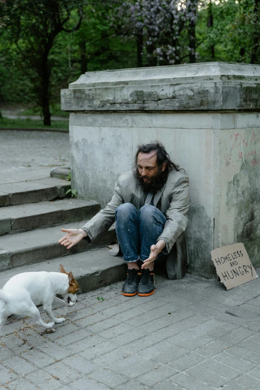 a man sitting on the steps with his dog and a sign