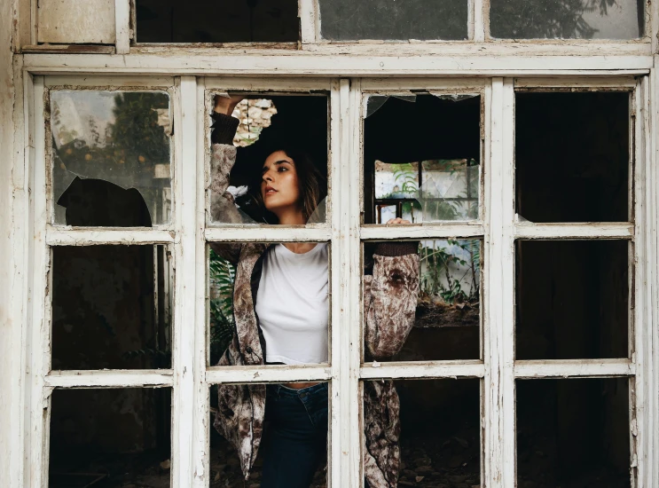 a woman is standing behind the bars of an old window