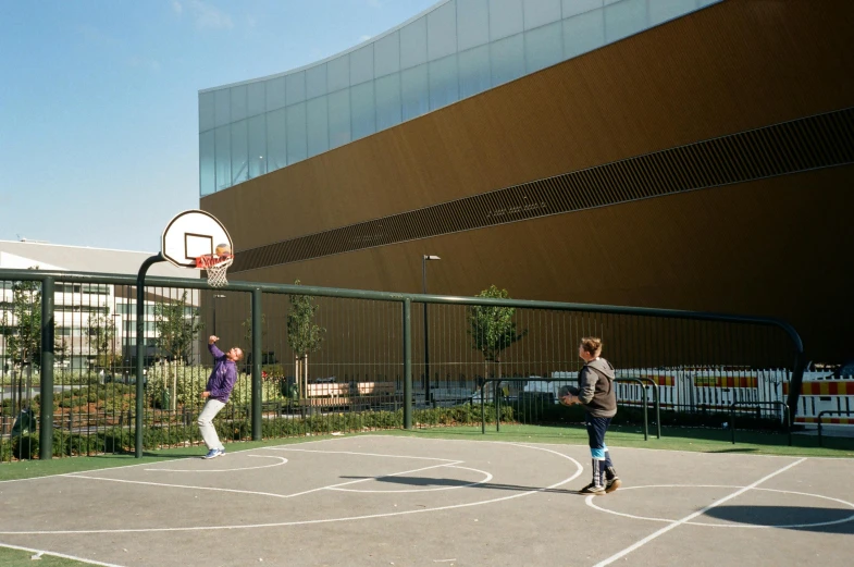 two people playing a game of basketball in an outdoor court