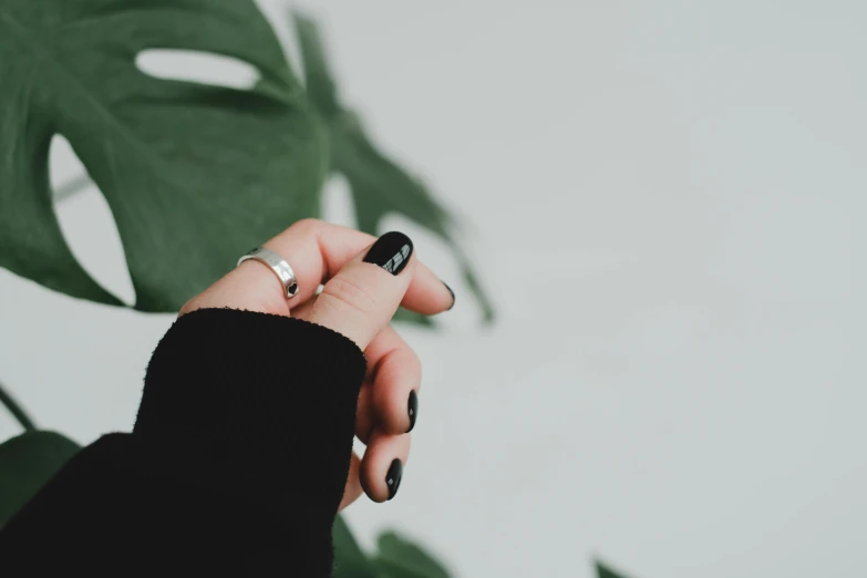 a person with their finger resting on their fingers, in front of a plant leaf