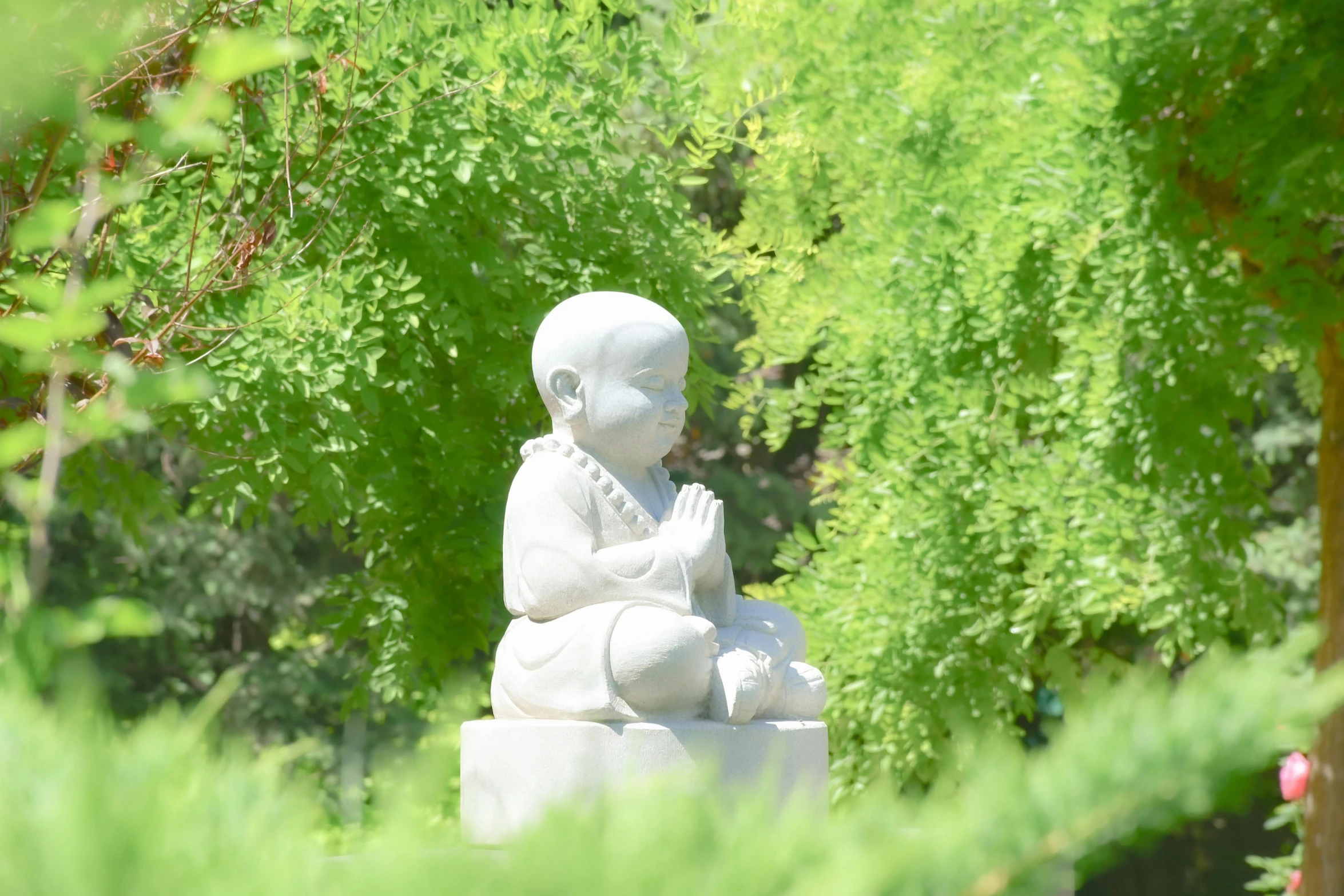 a white statue sitting in the middle of a forest