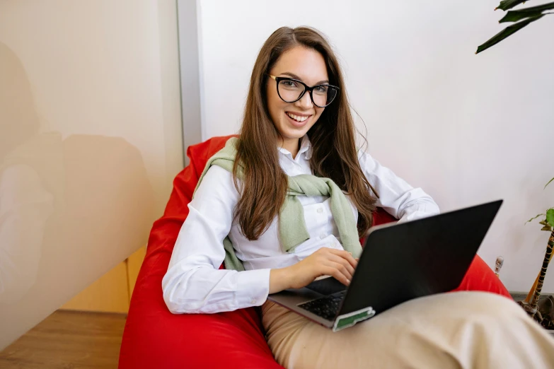 the smiling woman uses her laptop on the bean bag chair