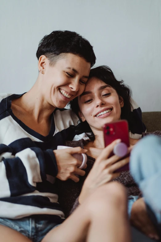 a couple sitting next to each other while looking at a phone