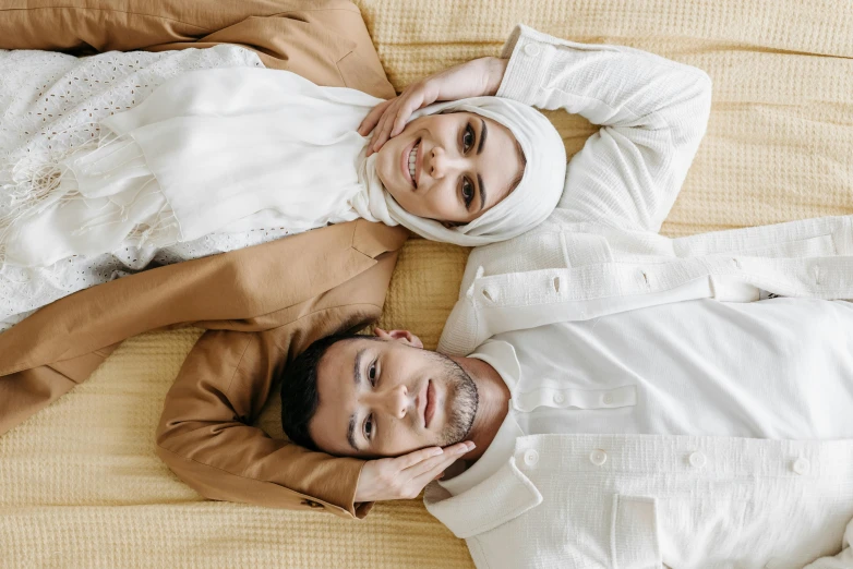 two people in islamic garb laying down on a bed