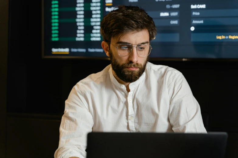 a man in glasses works on a laptop