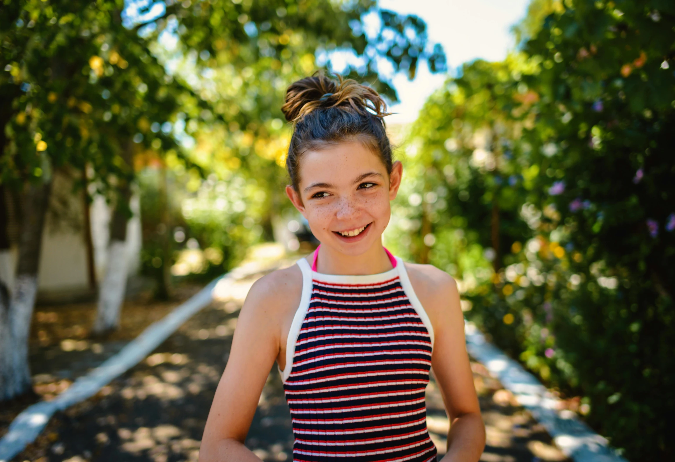 a smiling  in a striped top stands on a path