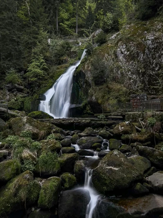 a waterfall with moss on the rocks is shown in this pograph