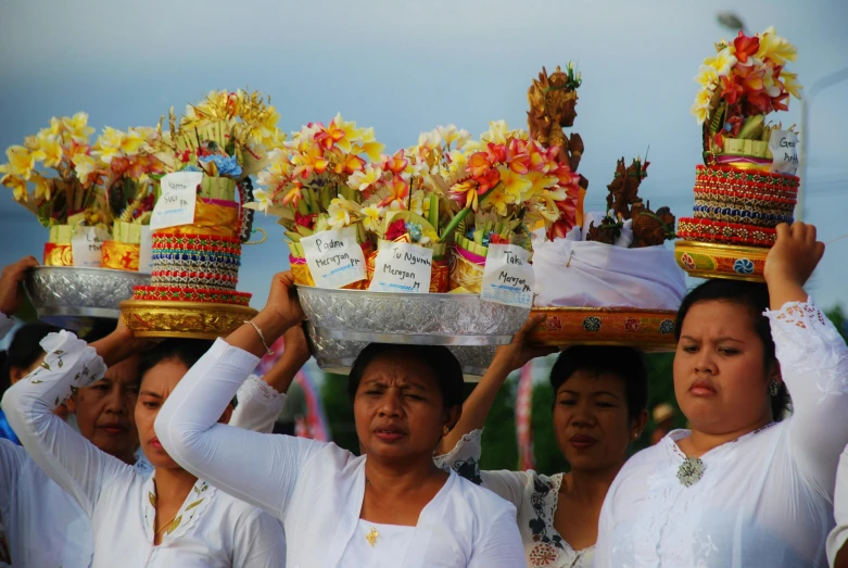 many woman are carrying baskets that have flowers on top