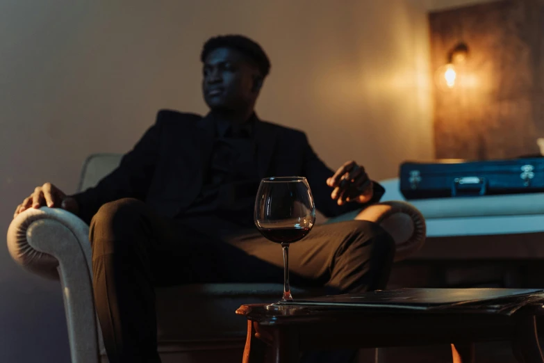 man sitting on chair with wineglass on table in room