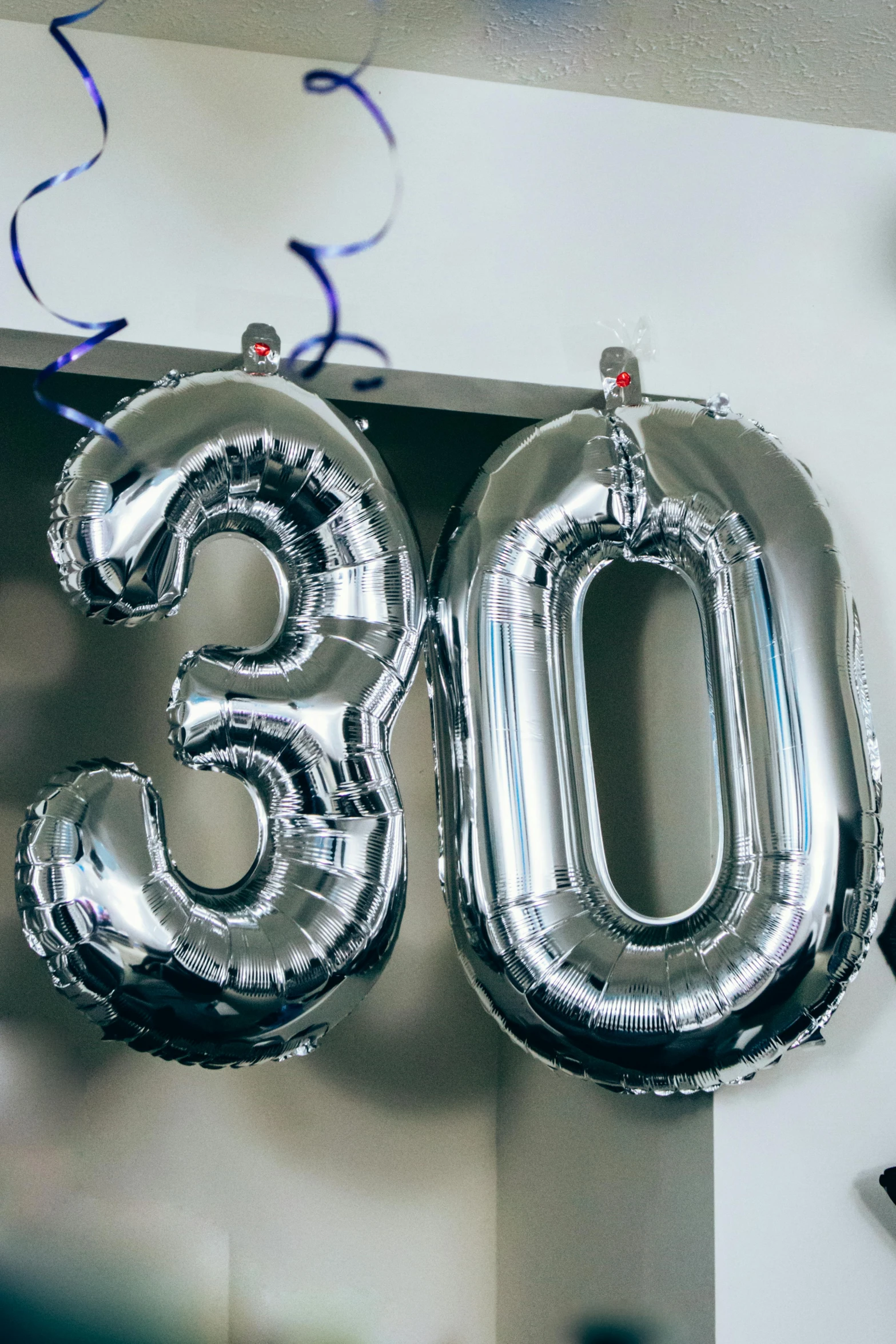 foil balloons hanging above a number shaped balloon