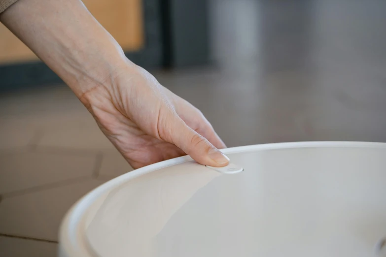 a person reaches out of a white bucket