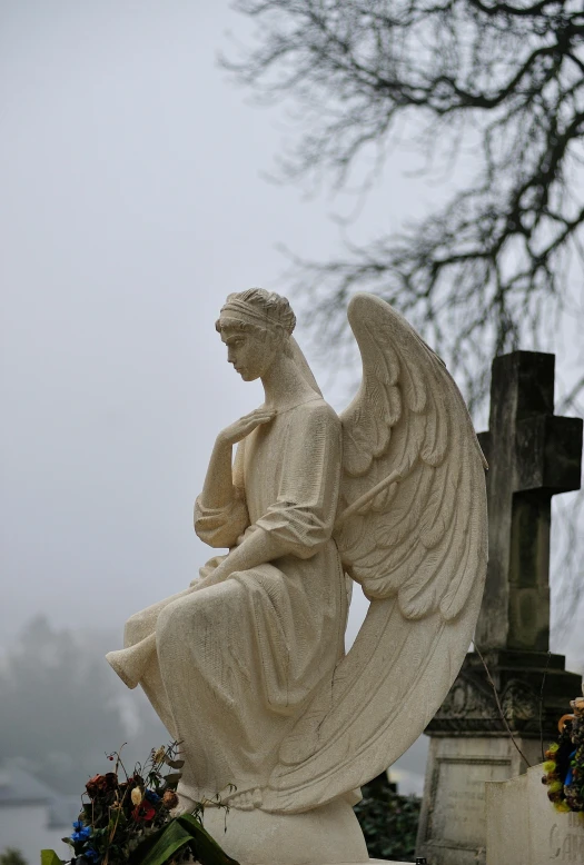 an angel statue sits on top of a gravestone
