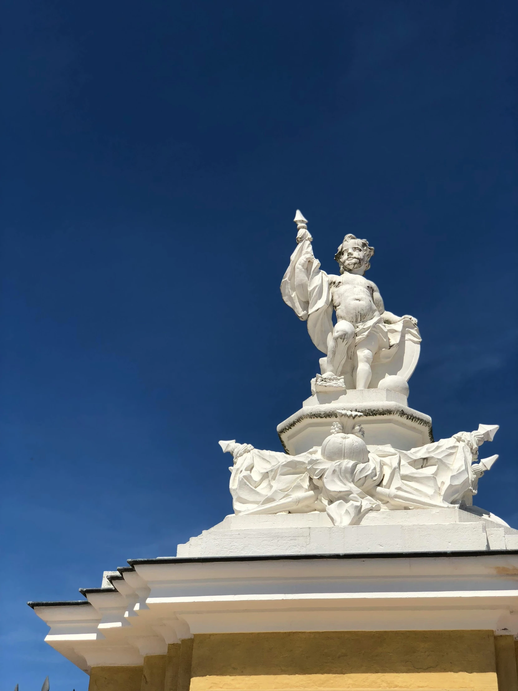 an statue on top of a building with blue skies