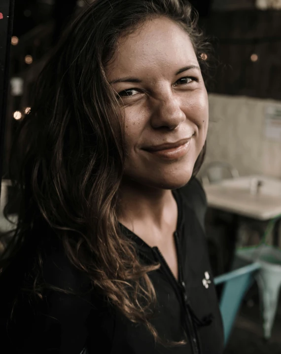 woman smiling and wearing black shirt by table