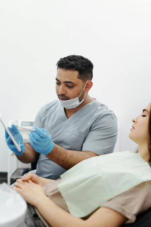 two people wearing gloves while getting ready for a dental procedure