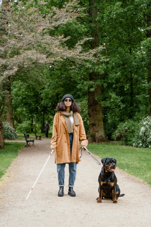 a lady walking her dog on a leash in the park