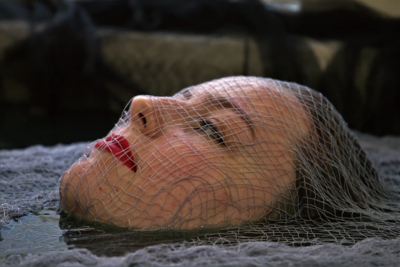 a mannequin head is lying in a net covered pool