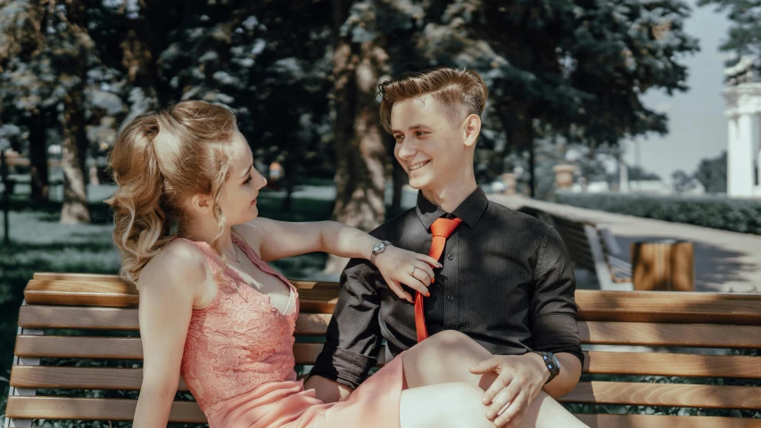 a boy sitting on a bench touching the girl's cheek