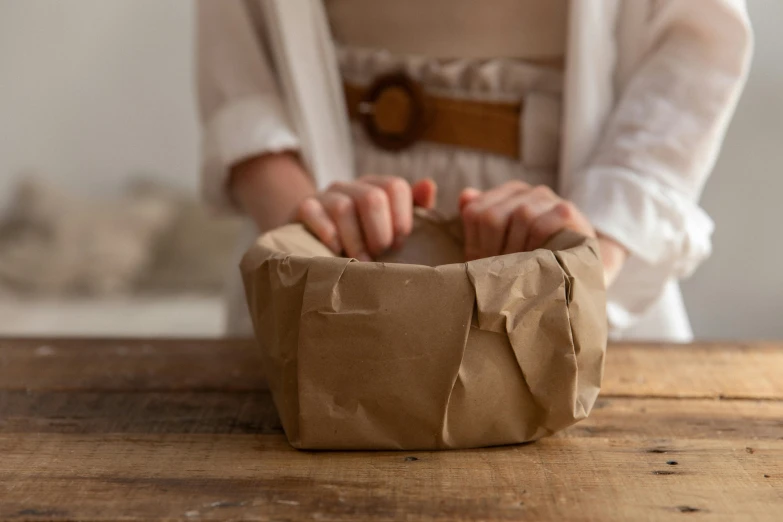 a woman is sitting at a table with her hand on a small container