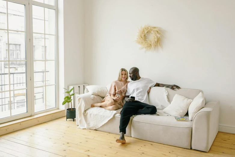 two people are sitting on a couch in a white living room