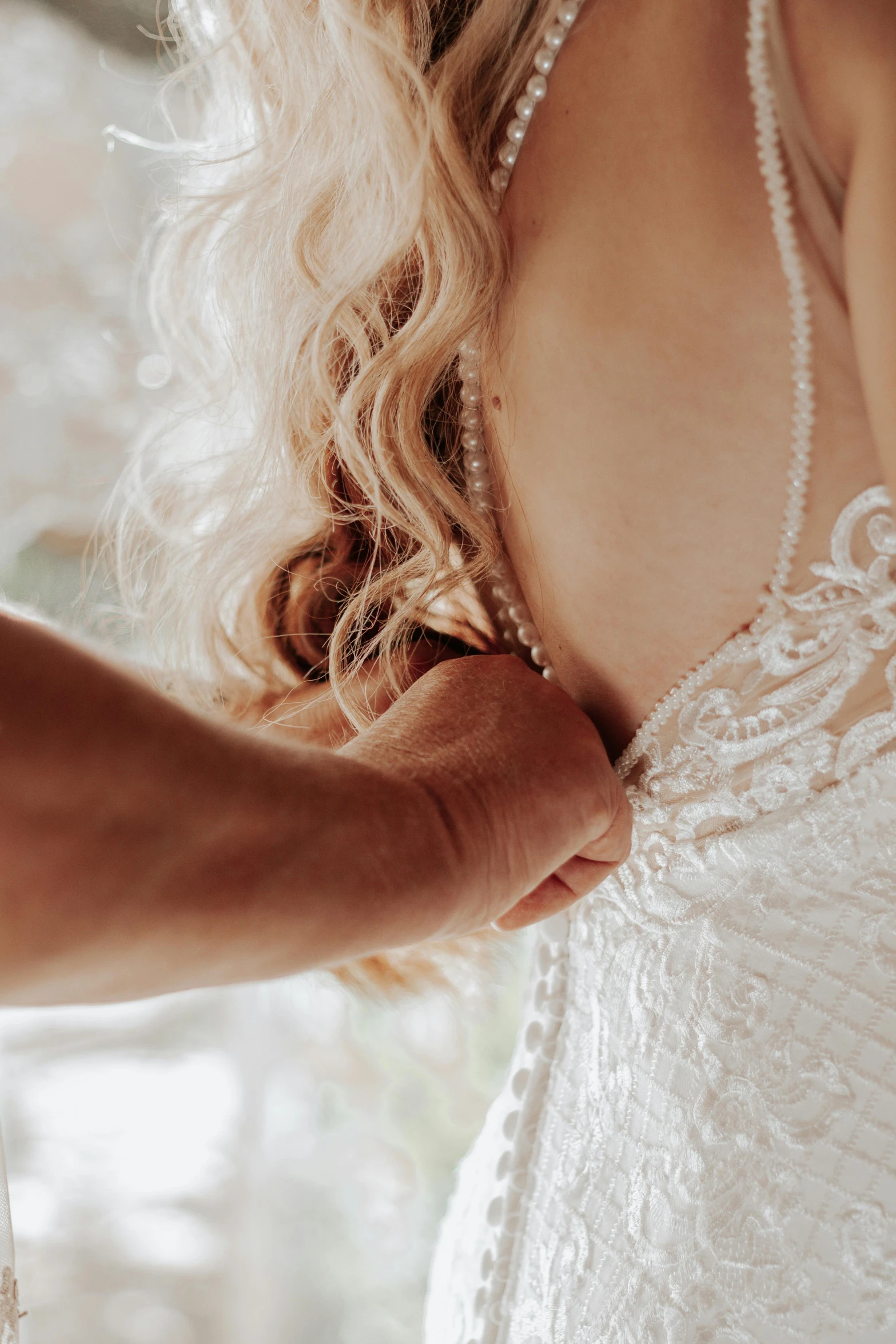 the back of a bridal gown being held by someone