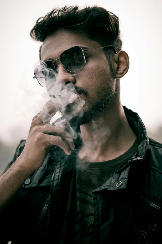 a man smoking an electronic cigarette outside in the sun