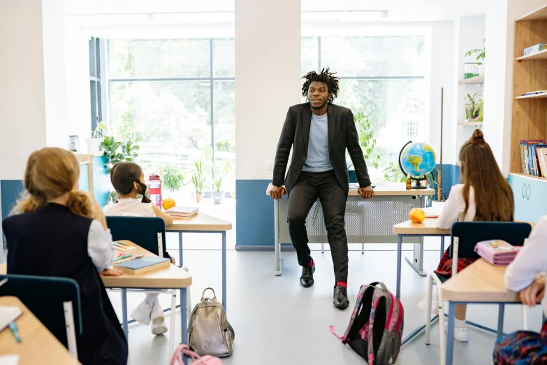 a man walks in to an open classroom with children