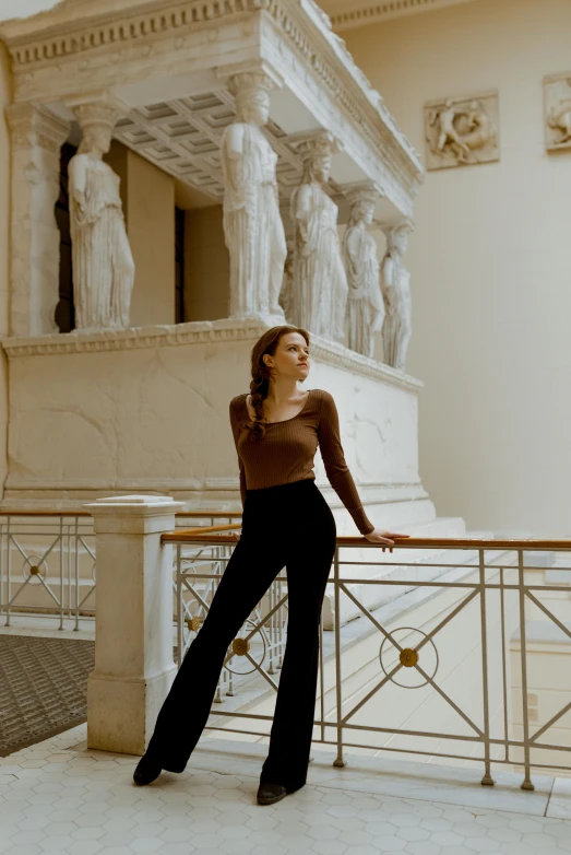 a woman leaning against a railing next to statues