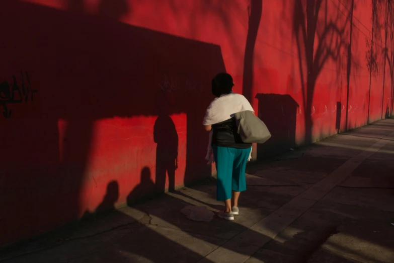 a person standing on the side walk near a wall with graffiti