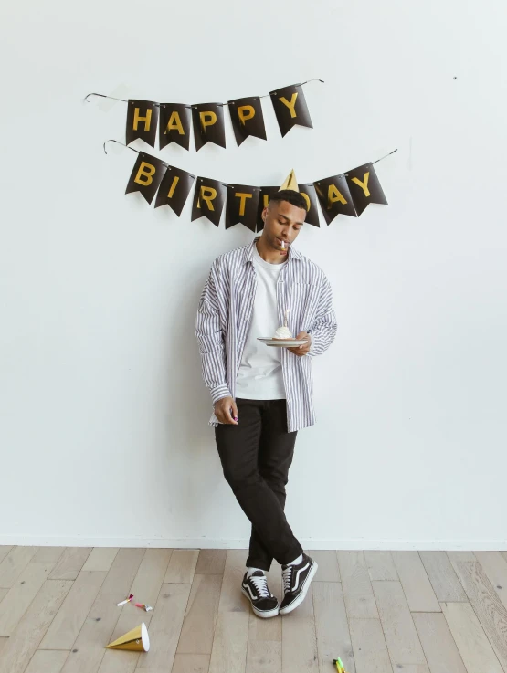 man dressed in casual clothing standing underneath banner with happy birthday