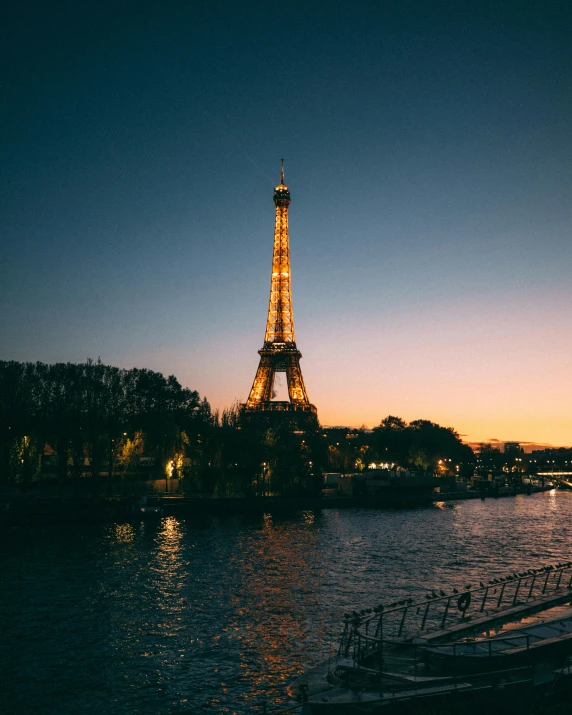 the eiffel tower lit up at night and reflecting in water