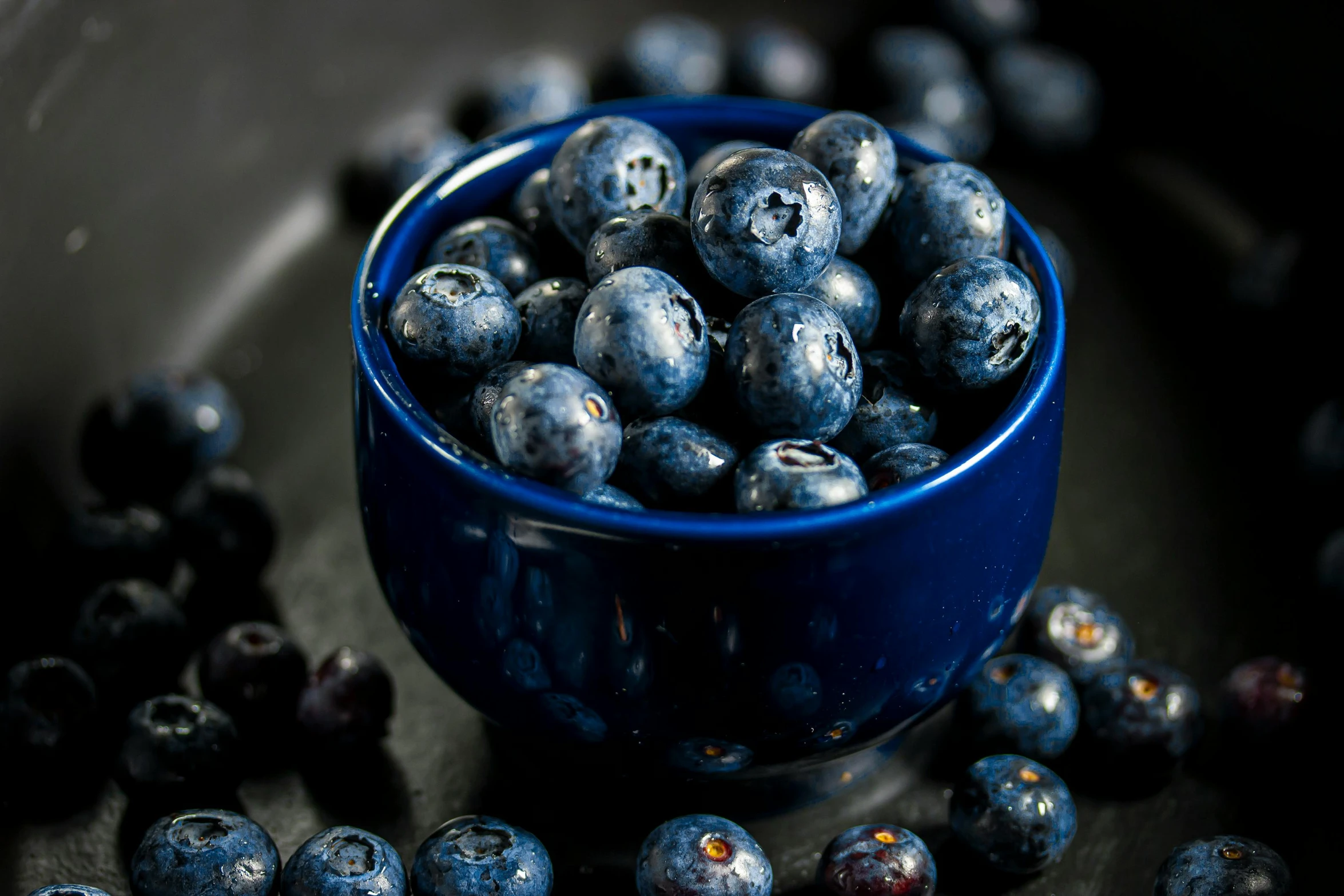 a small blue bowl is full of ripe berries