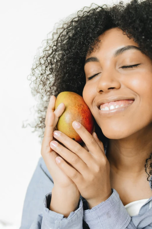 a smiling woman holding an apple to her face