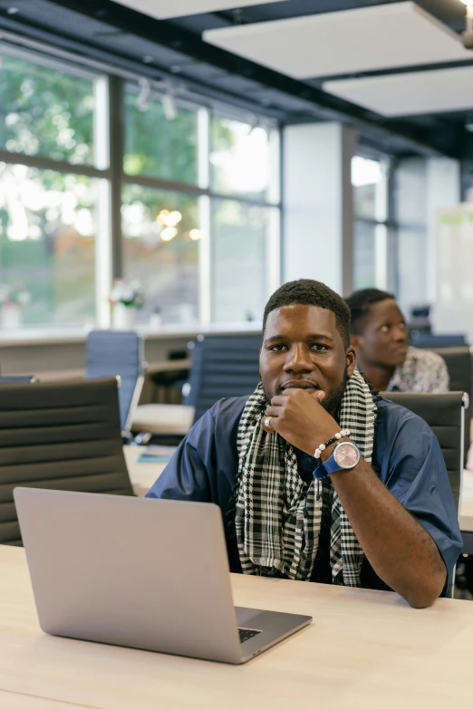 man in shirt and scarf sitting at table with laptop computer