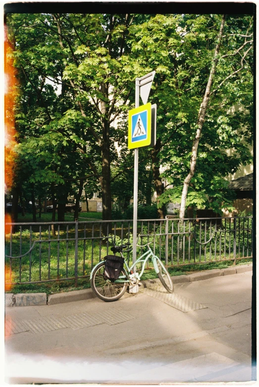 a bicycle  to a sign post in a public park