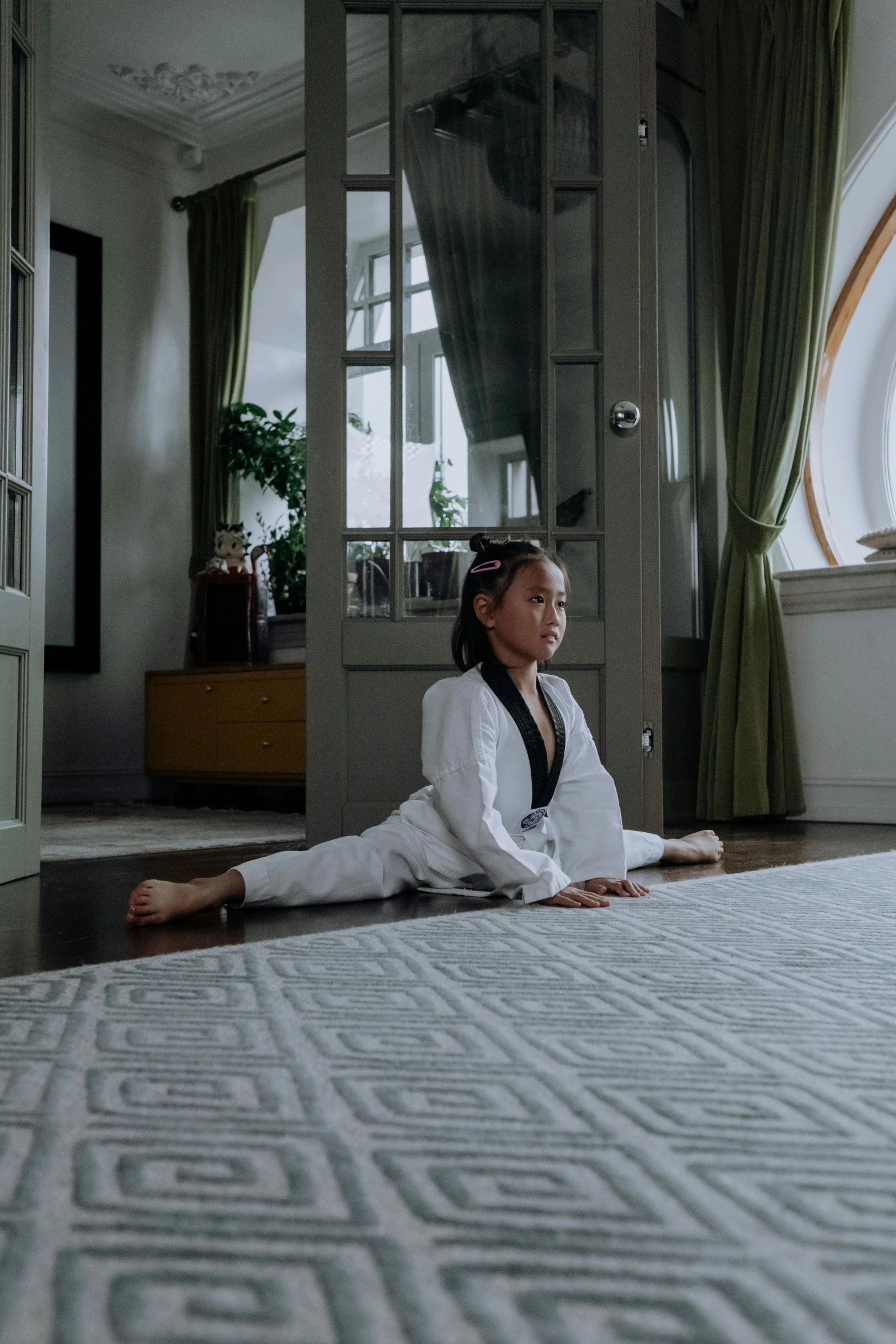 an asian woman sits on a rug in front of a doorway