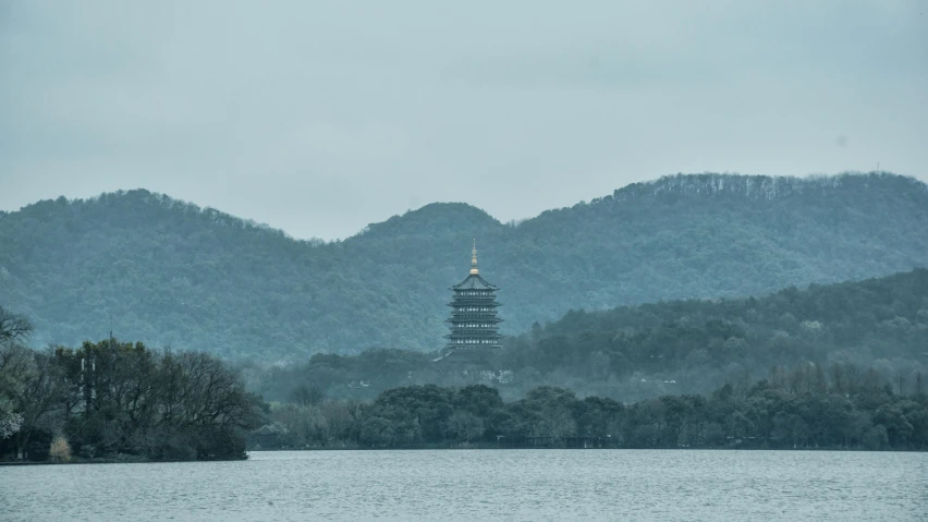 the pagoda is overlooking a lake with mountains in the distance