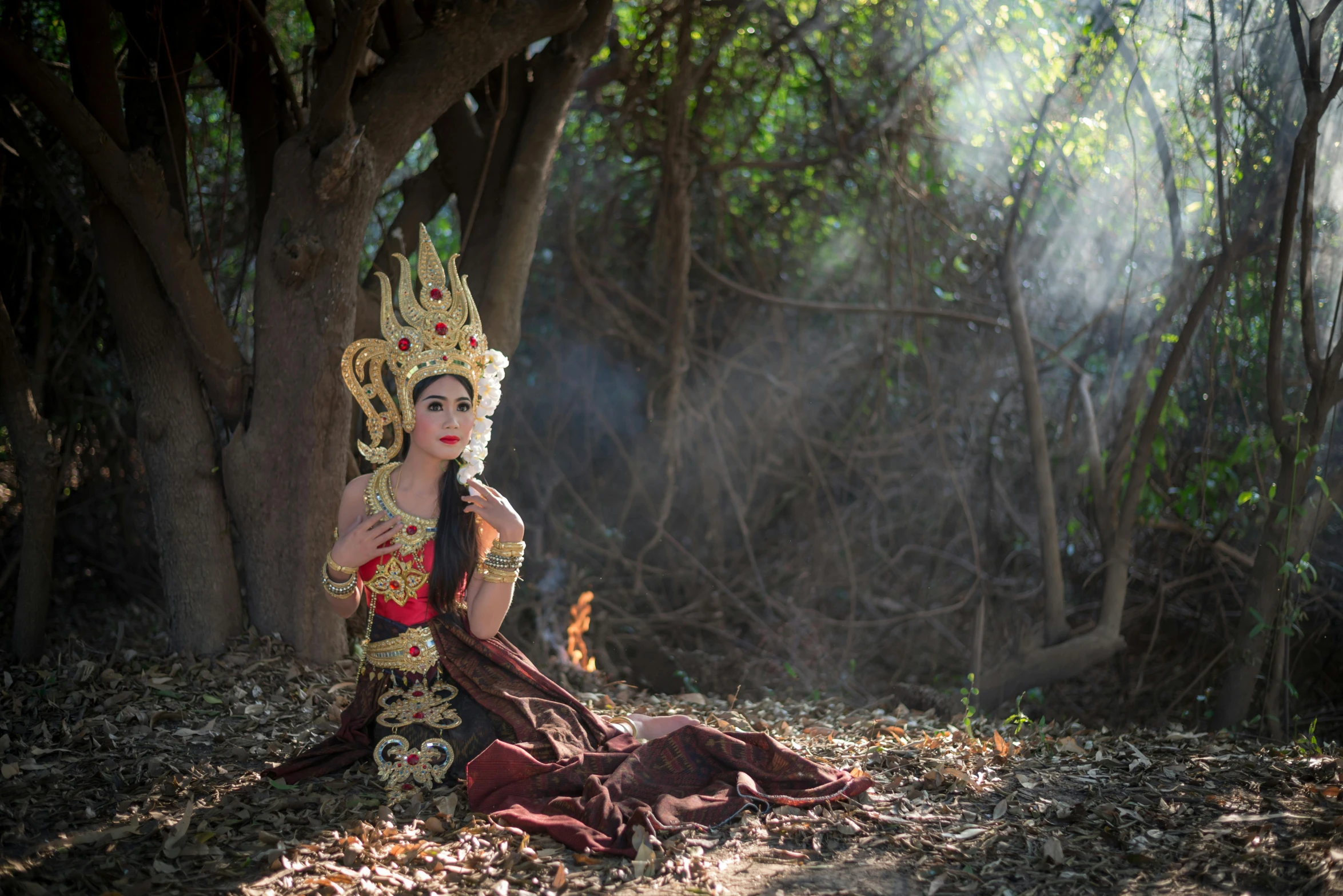 a woman sitting next to trees and a forest