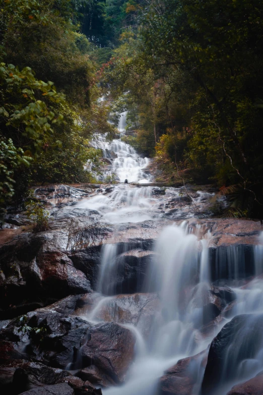 a long and skinny waterfall flows out of some rocks