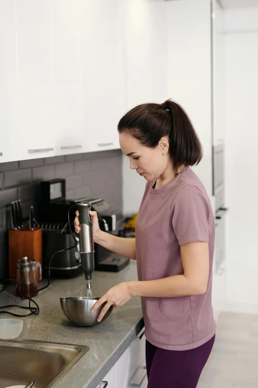 a woman using a mixer on top of a sink