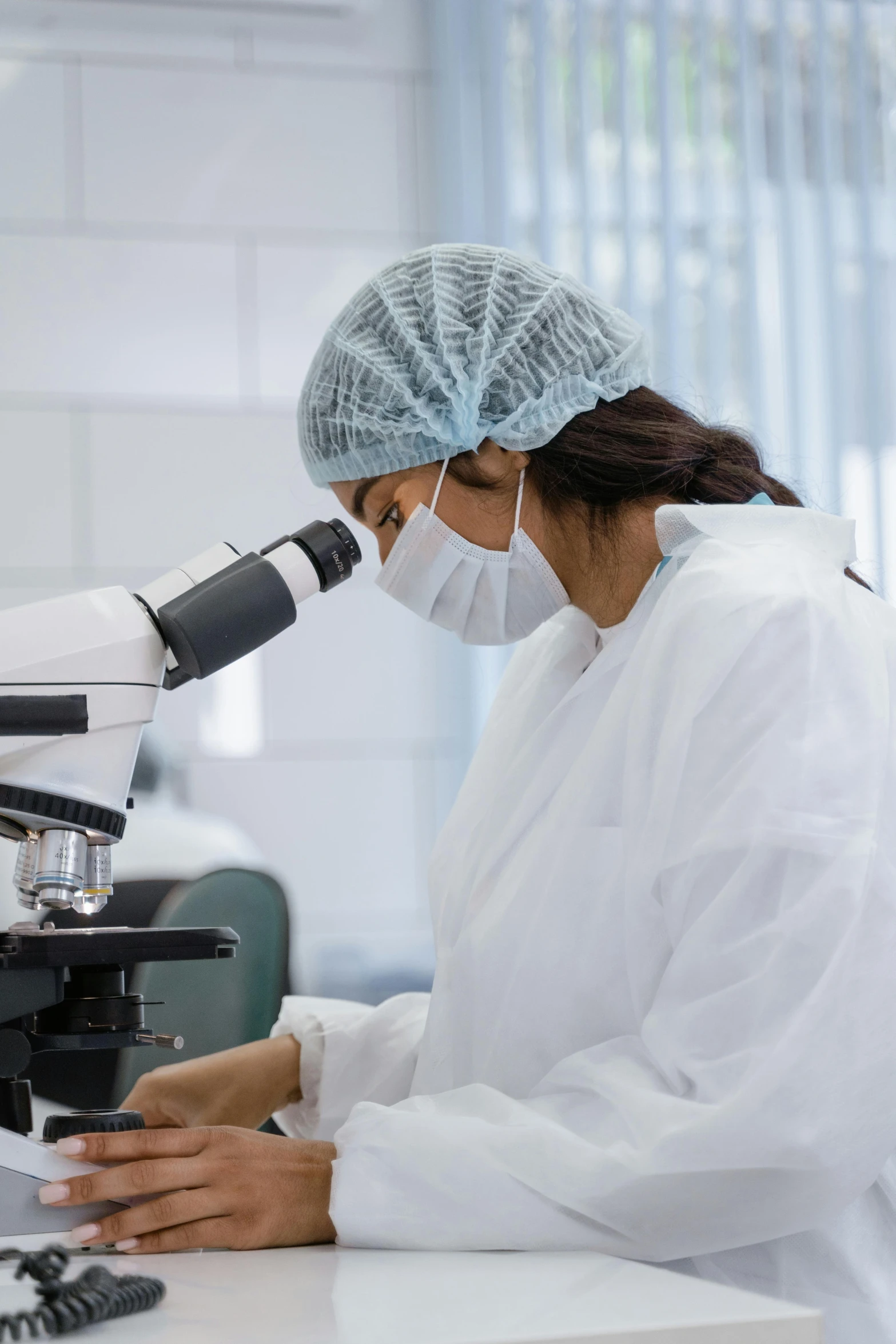 woman wearing white uniform and a medical mask is working in a laboratory