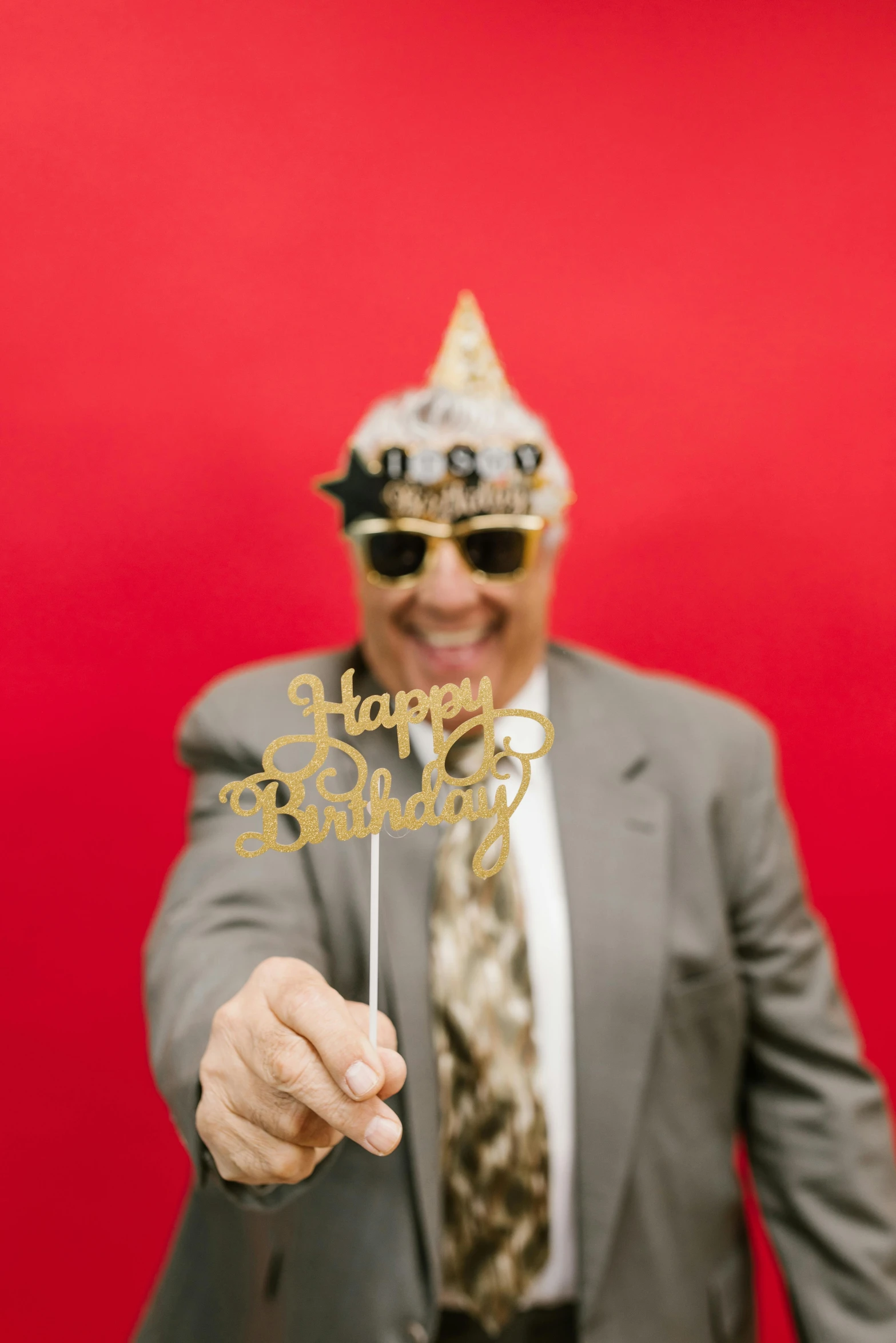 an african american man in glasses wearing a suit and a mask holding a happy birthday cake